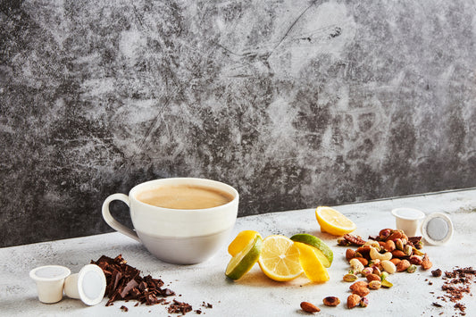 a table topped with a mug of Ola coffee, some Ola home compostable coffee capsules, plus fruit and nuts